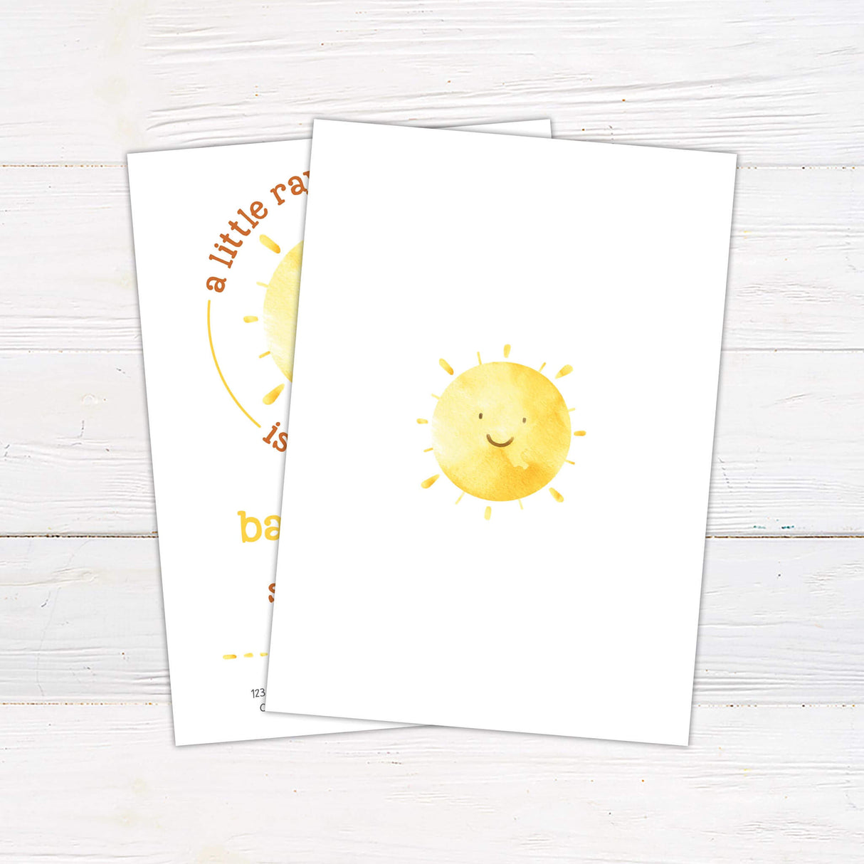 Baby shower invitation featuring a cheerful watercolor sun with a smiling face. The phrase "A little ray of sunshine is on the way" curves around the sun in warm tones. The design includes playful yellow and orange typography with event details below, honoring the mom-to-be. A soft, light background complements the bright and inviting theme.
