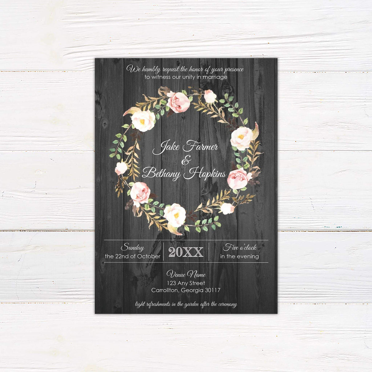 Rustic wedding invitation with floral rose wreath on a dark wood background and elegant white script and serif fonts for a country-themed celebration.