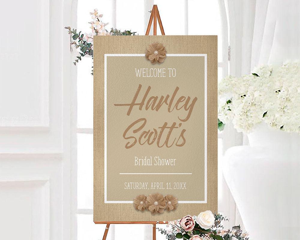 A rustic burlap bridal shower sign with burlap flowers and neutral tan background. The design features simple text and farmhouse-style accents.