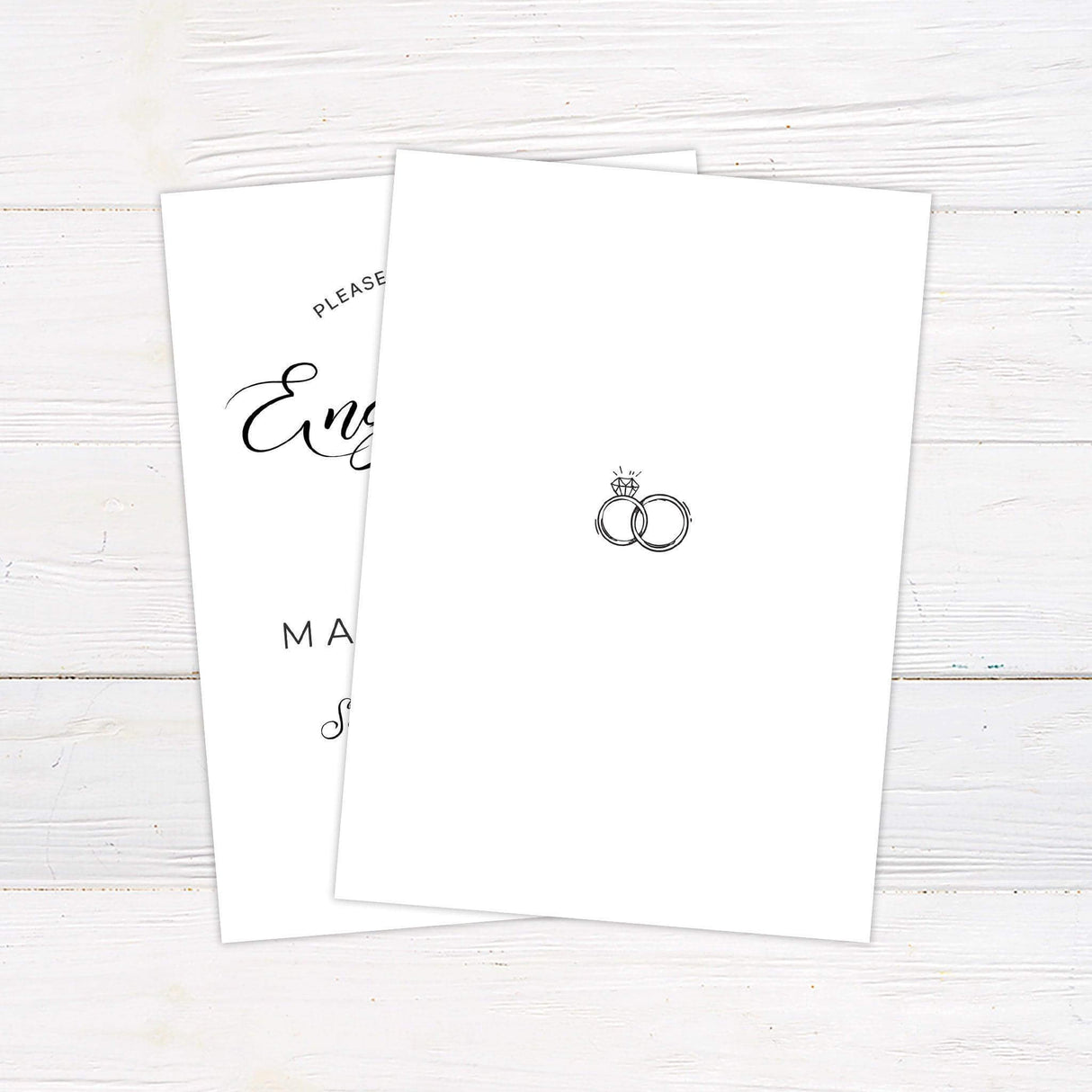 Elegant black and white engagement party invitation featuring modern script and serif fonts with an illustration of two interlocking rings and a diamond icon. Includes customizable text for date, time, and venue. Professionally printed on white background with minimalist design. Back