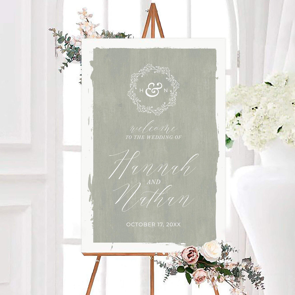 Green seafoam canvas wedding welcome sign with a textured canvas background, white calligraphy, and a delicate botanical monogram wreath. The personalized design features the couple’s names, initials, and wedding date.