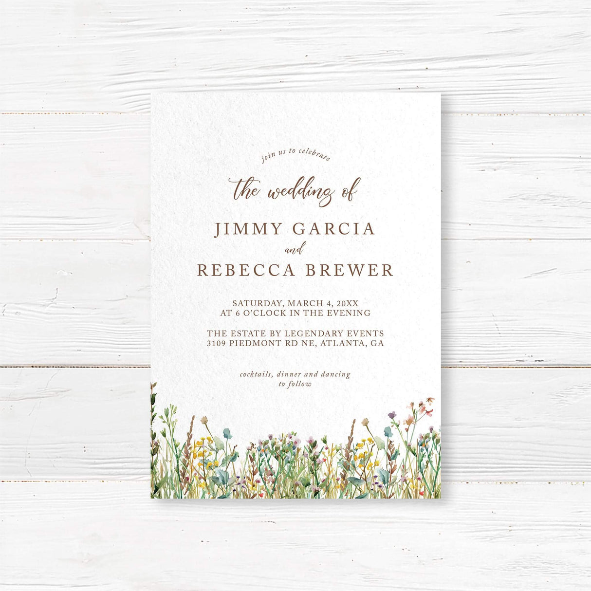 Elegant wedding invitation with a minimalist design featuring delicate script and serif fonts. The bottom of the invitation is adorned with a watercolor wildflower border, adding a rustic and romantic touch. The text includes event details such as the date, time, and venue, with a note about cocktails, dinner, and dancing to follow. The color palette consists of soft neutrals and earth tones, creating a timeless and sophisticated look.