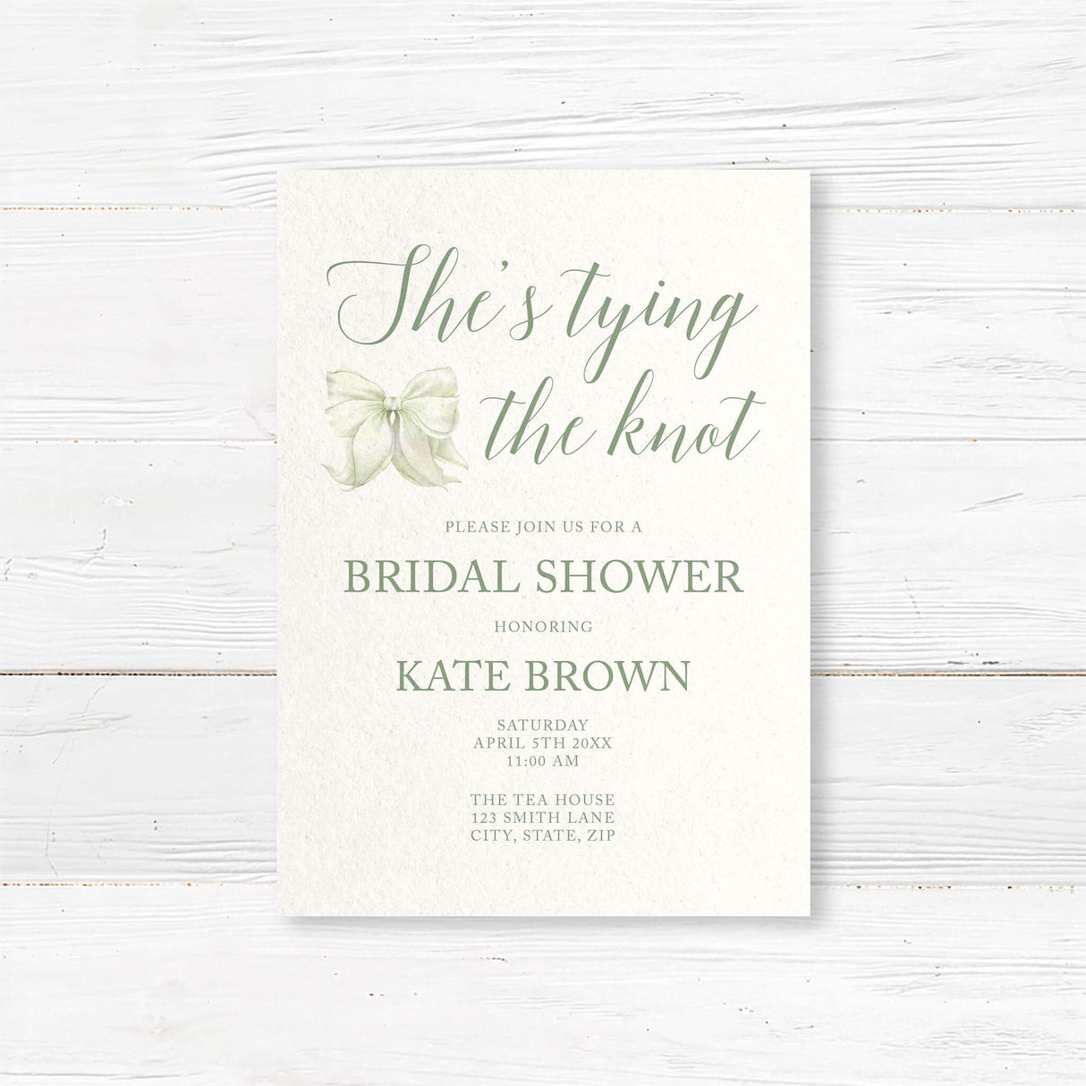 Watercolor bow bridal shower invitation that reads "She’s Tying the Knot" with floral accents,