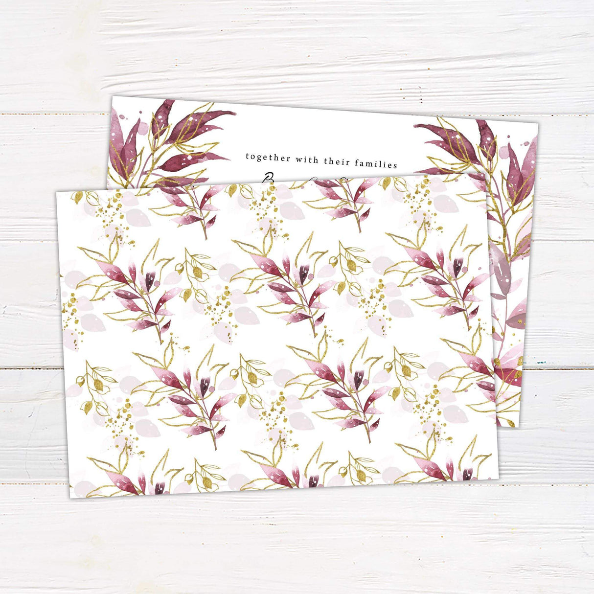 Wedding invitation with burgundy and blush watercolor leaves, gold botanical accents, and elegant script and serif fonts on white cardstock.