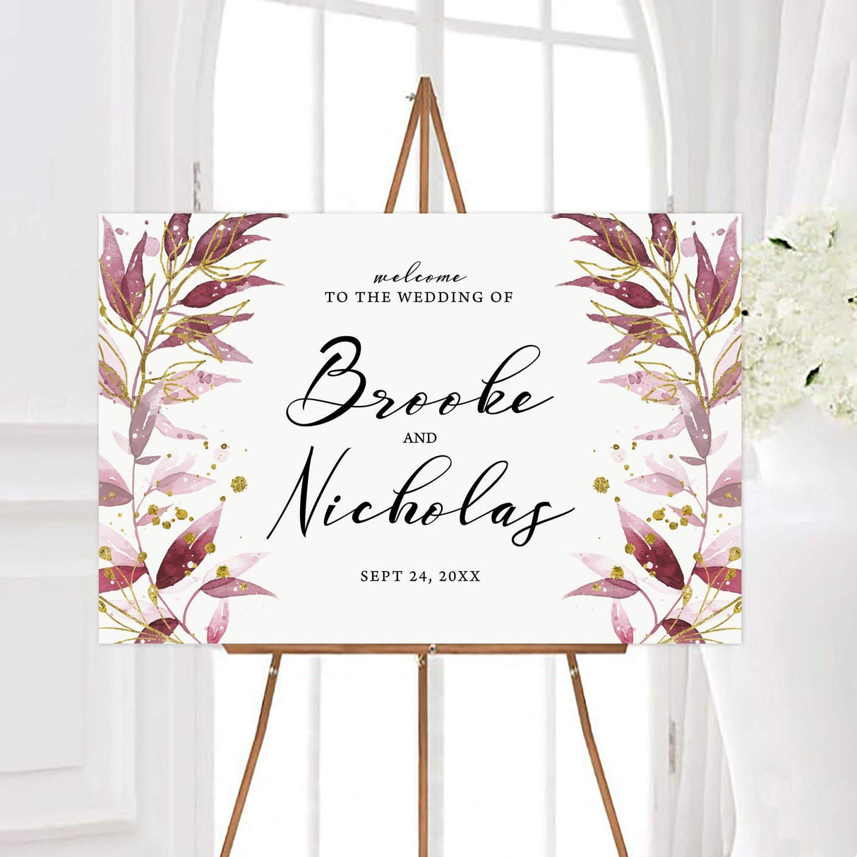 Shimmering sprigs wedding welcome sign with mauve, burgundy, and blush botanical sprigs accented by shimmering gold details. Large black script displays the couple’s names with their personalized wedding date below.