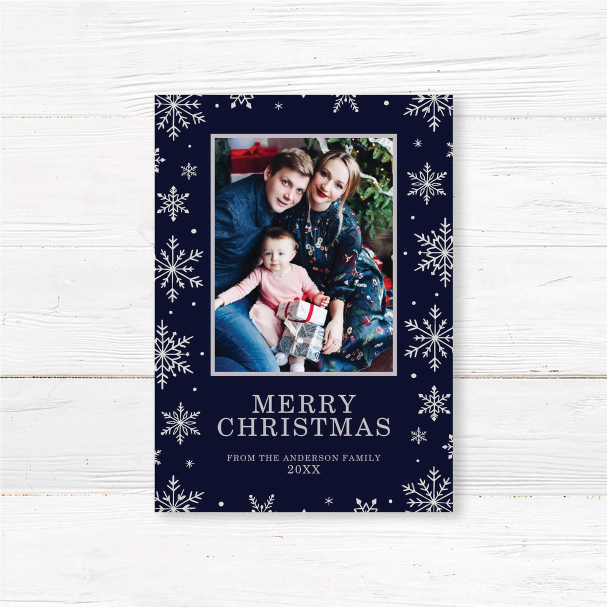 Christmas card with navy blue background, silver snowflakes, and a centered family photo. Includes “Merry Christmas” and a custom family name and year.