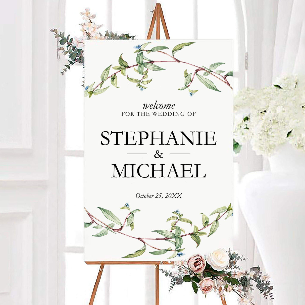 Simple branches wedding welcome sign with green leafy branches, tiny blue flowers, and personalized black lettering. The couple’s names and wedding date are centered on a clean white background.