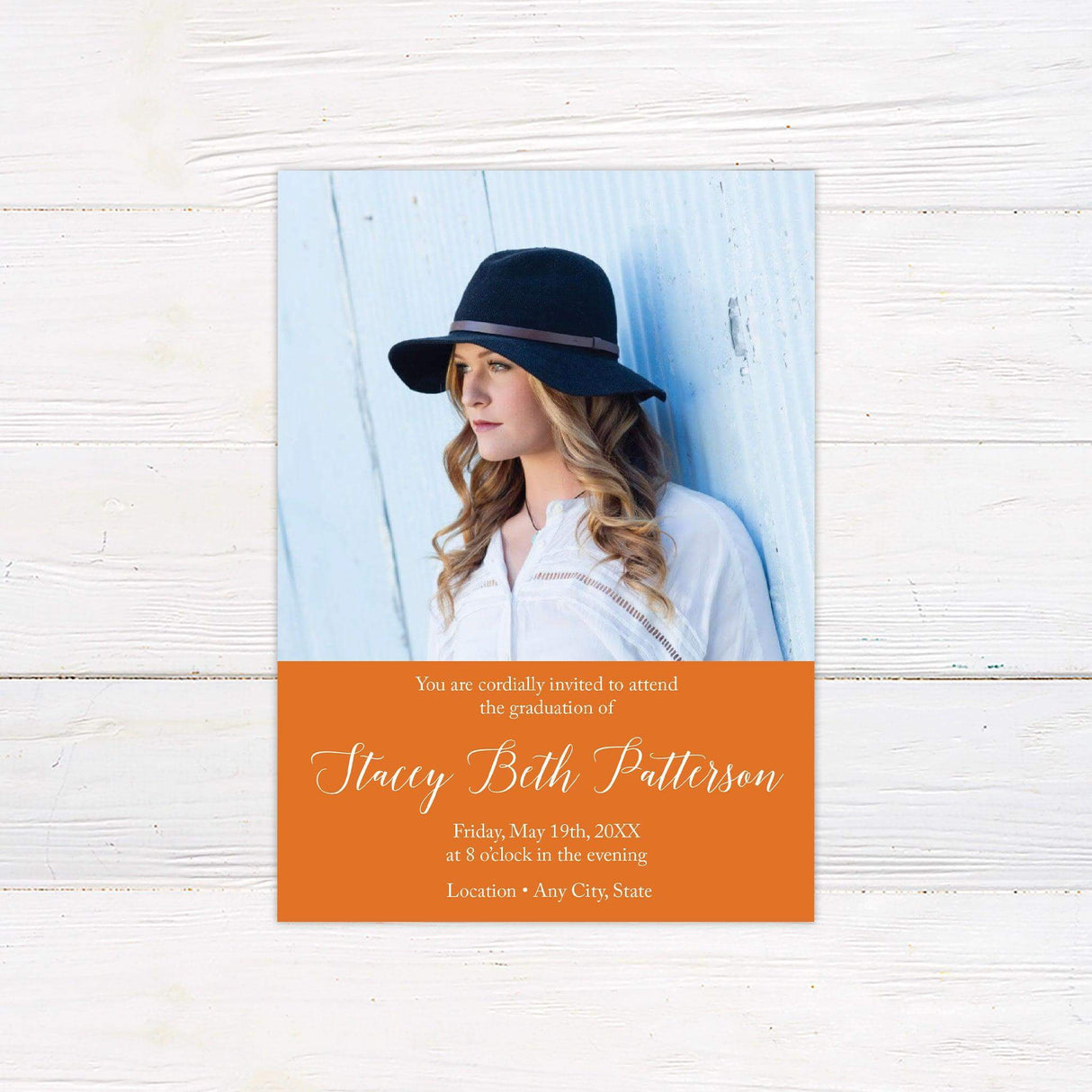 The front of a graduation invitation displaying a split design with a large photo and graduation details in an elegant font in a custom color block.  Orange.