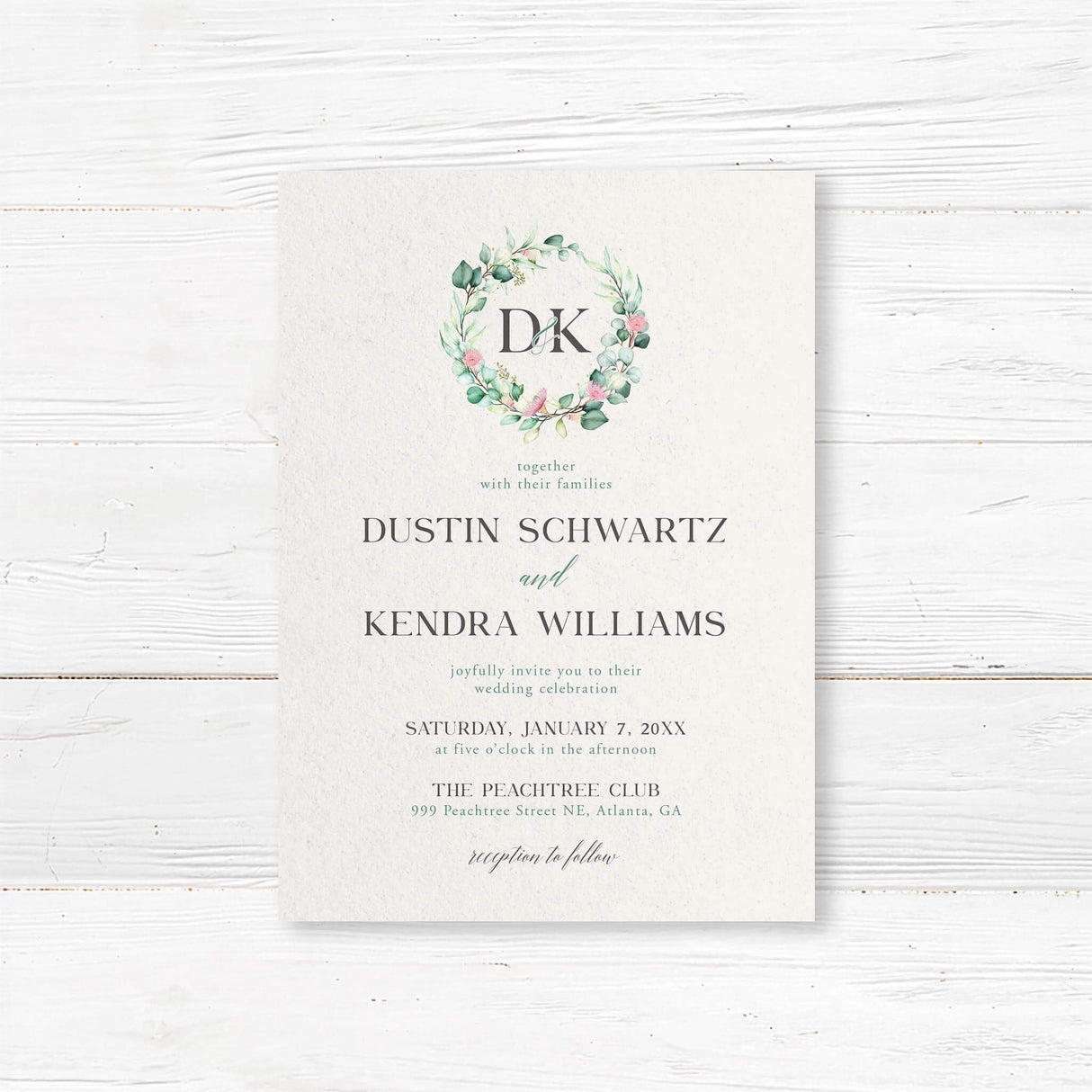 Wedding invitation with botanical wreath monogram, soft watercolor greenery, serif and script fonts on textured white paper