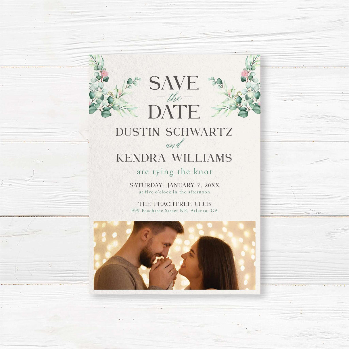Save the date card with green wreath monogram and serif fonts on ivory background