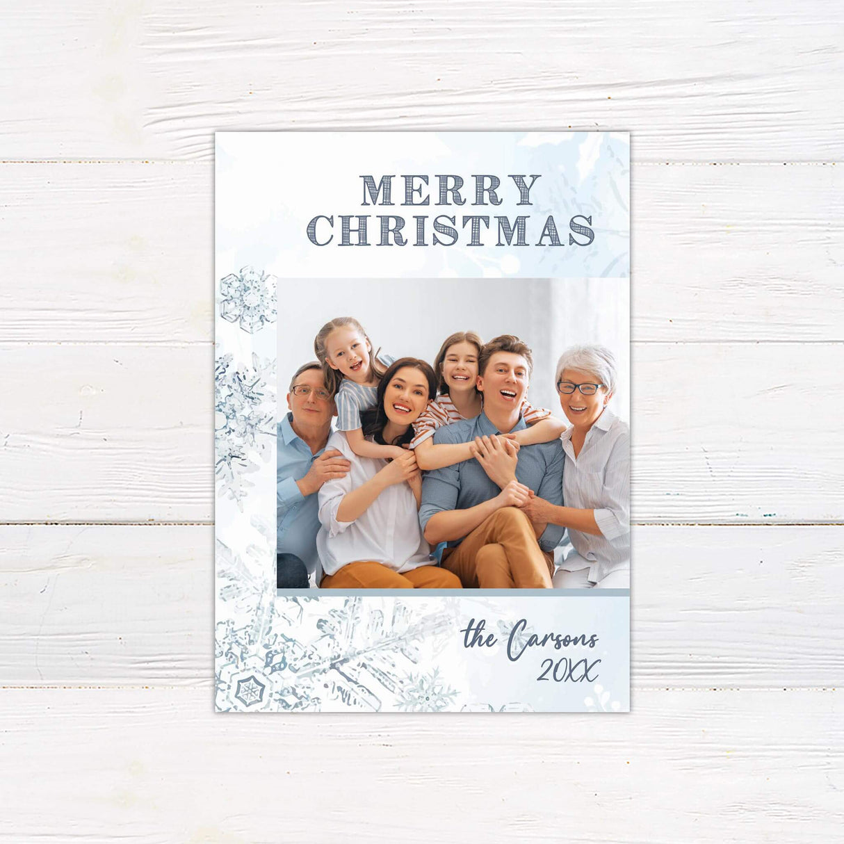 A Christmas card with snowflake designs and a family photo in the center. The card includes “Merry Christmas” with customizable family name text.