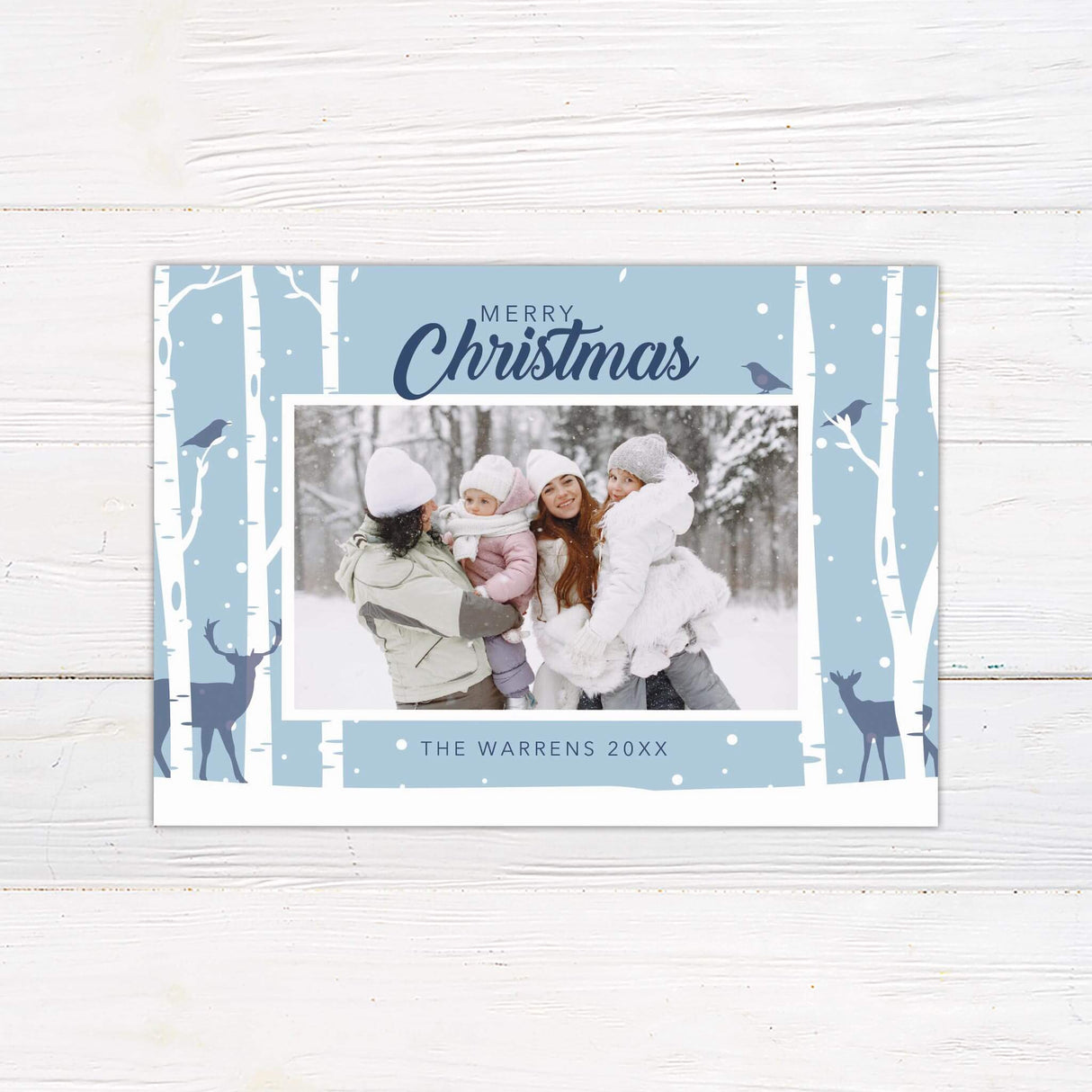 A holiday card with snowy birch trees, deer silhouettes, and a family photo in the center. The card includes “Merry Christmas” with customizable family text.