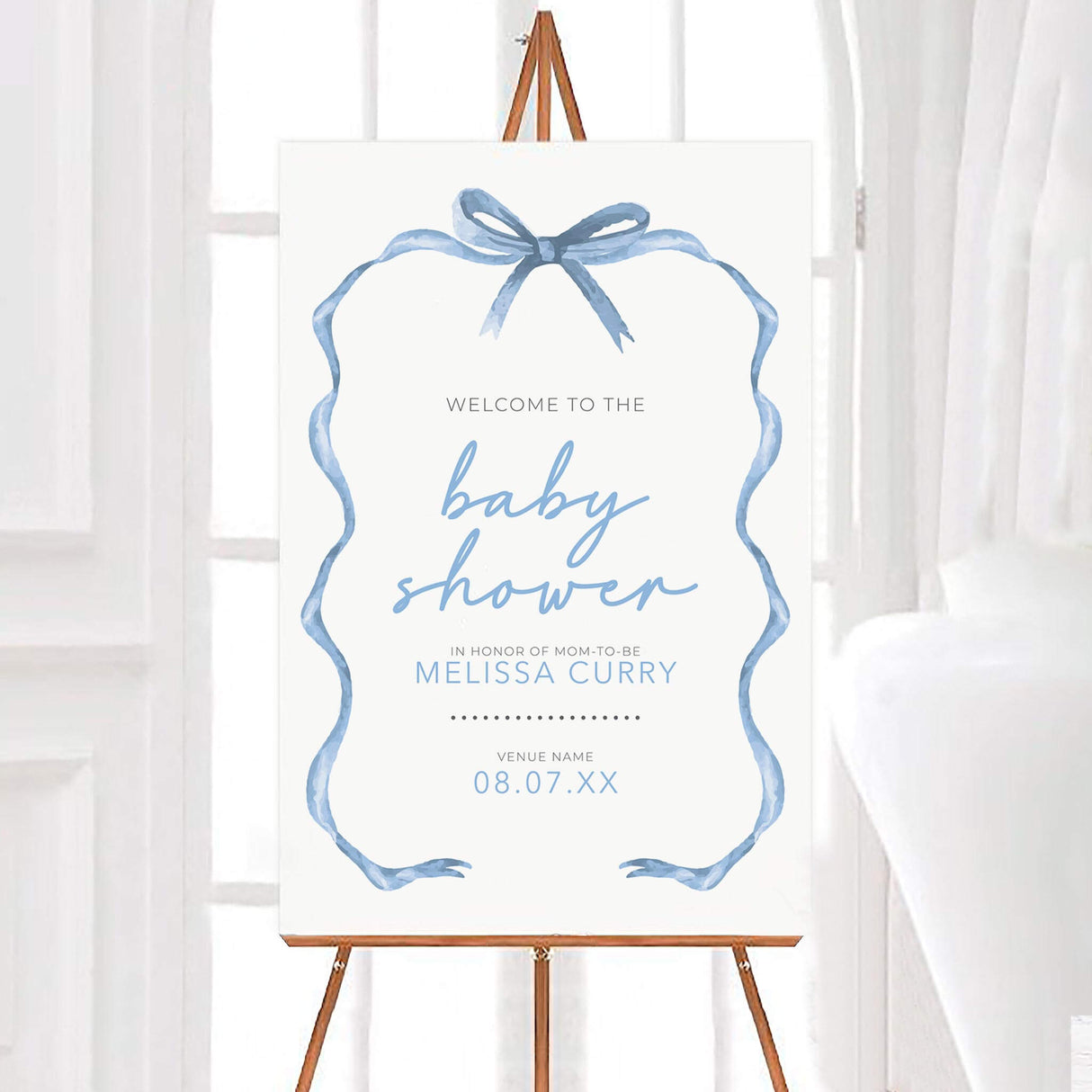 Blue ribbon baby shower invitation on easel with elegant typography, ideal for gender-neutral celebration.