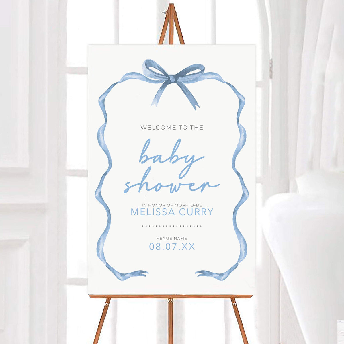 Personalized tied with a ribbon baby shower welcome sign featuring a soft blue watercolor ribbon frame with a delicate bow at the top and elegant script lettering. The design includes customizable name, venue, and event date details on a clean white background.
