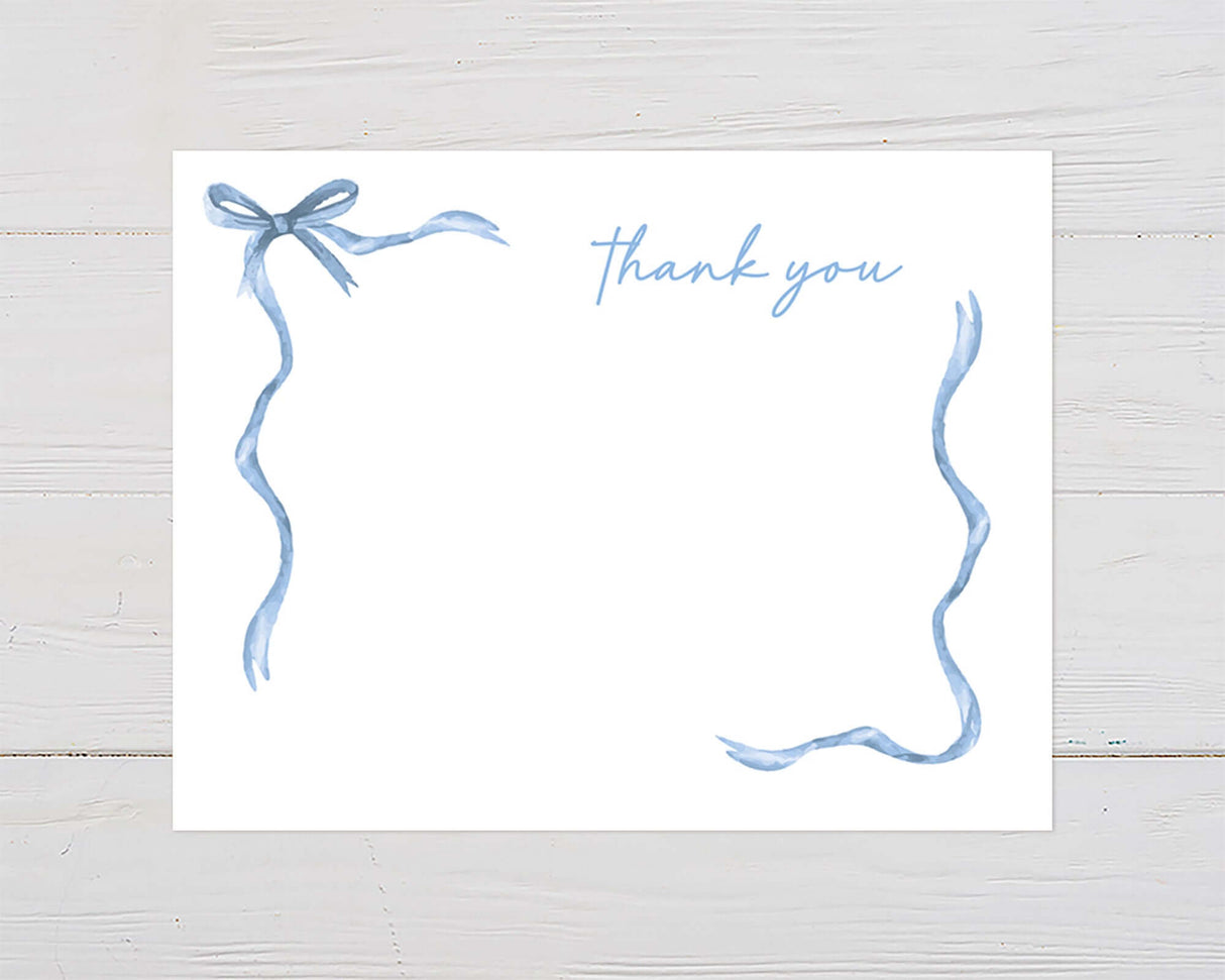 Thank you card with blue ribbon border on wooden background, featuring elegant hand-painted design.
