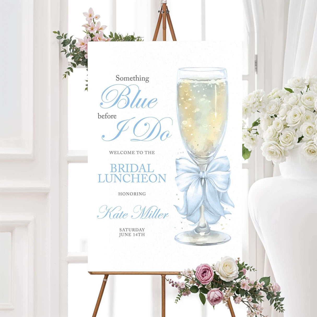 Bridal luncheon welcome sign with watercolor champagne glass, soft blue satin bow, and elegant blue text displayed on an easel with floral accents