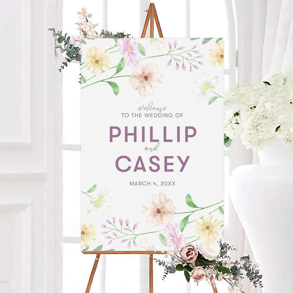 Pastel spring bouquet wedding welcome sign featuring pink, peach, yellow, and white wildflowers with green leafy stems. The personalized design displays the couple’s names and wedding date in mauve and neutral typography.