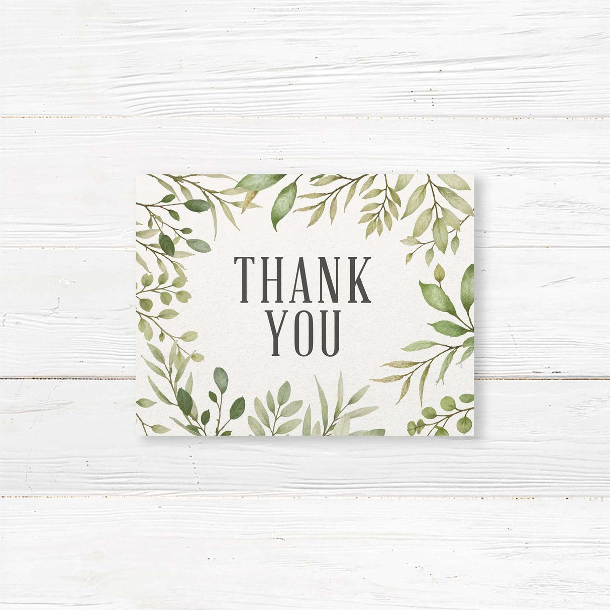 Floral wedding thank you card featuring delicate green foliage and stylish handwritten calligraphy. Printed on premium cardstock with matching envelopes. Available in folded or flat formats. A heartfelt way to express gratitude for weddings, bridal showers, and engagements.