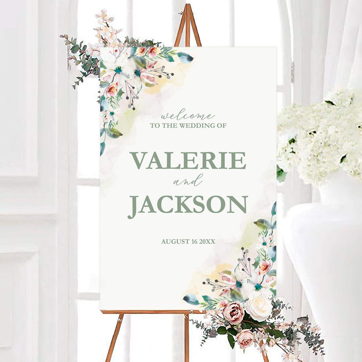 Personalized spring floral spray wedding welcome sign with watercolor white and blush flowers, blue-green leaves, and sage green lettering. The design features the couple’s names and wedding date on a soft white background.