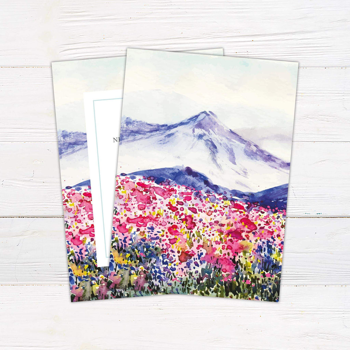 Spring wedding invitation with watercolor wildflower field and mountain landscape, featuring elegant serif and script fonts.- back side