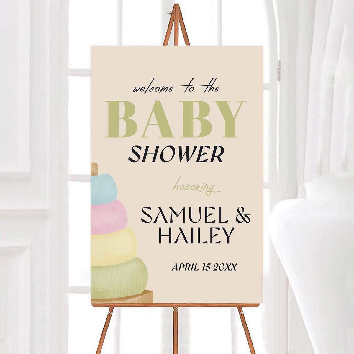 Personalized stacking rings baby shower welcome sign featuring a pastel watercolor stacking rings toy with soft blue, pink, yellow, and green colors on a cream background. The design includes elegant baby shower lettering with customizable names and celebration date.
