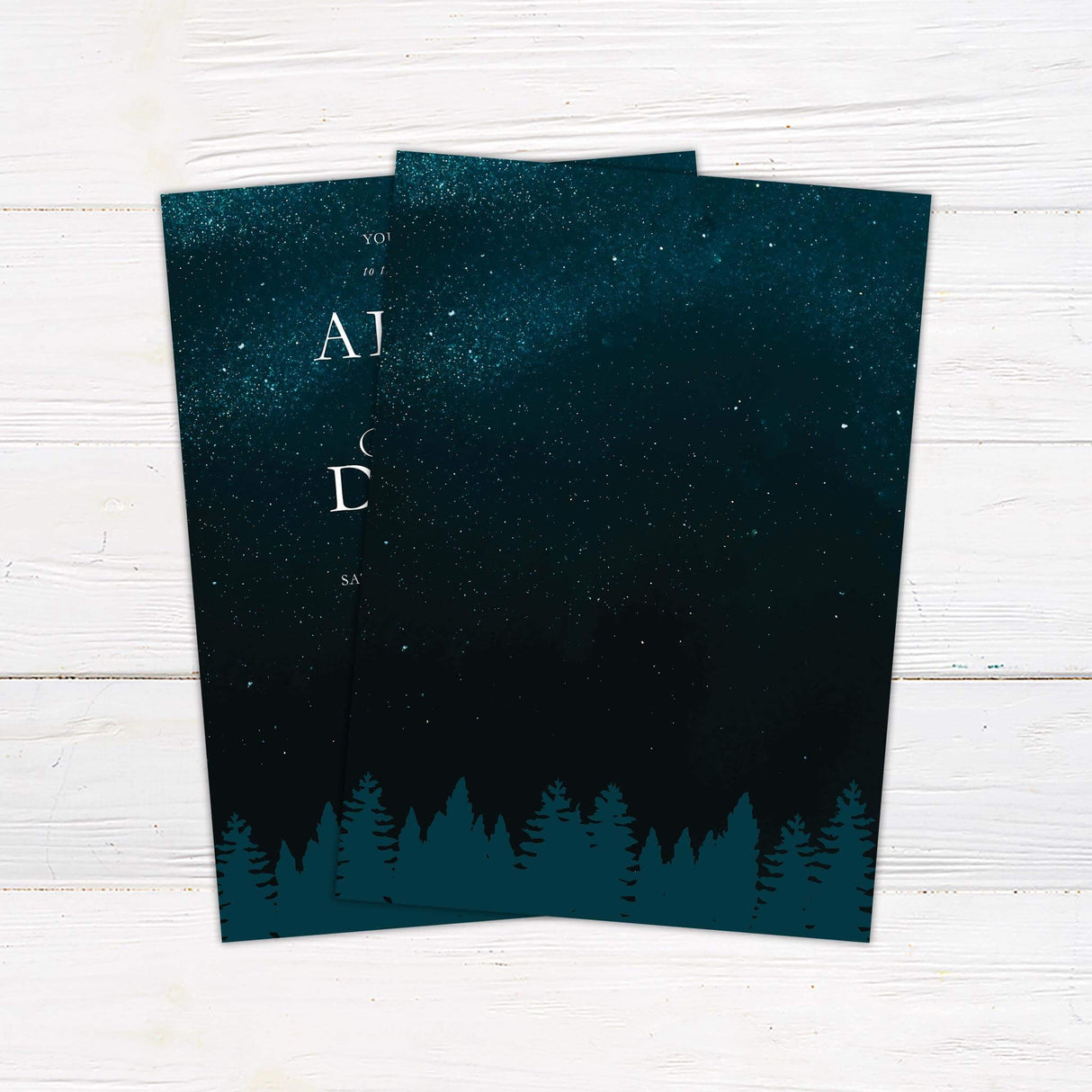 Wedding invitation with dark teal starry sky, silhouetted pine forest treeline, and elegant serif and script fonts for a romantic celestial wedding. - back side