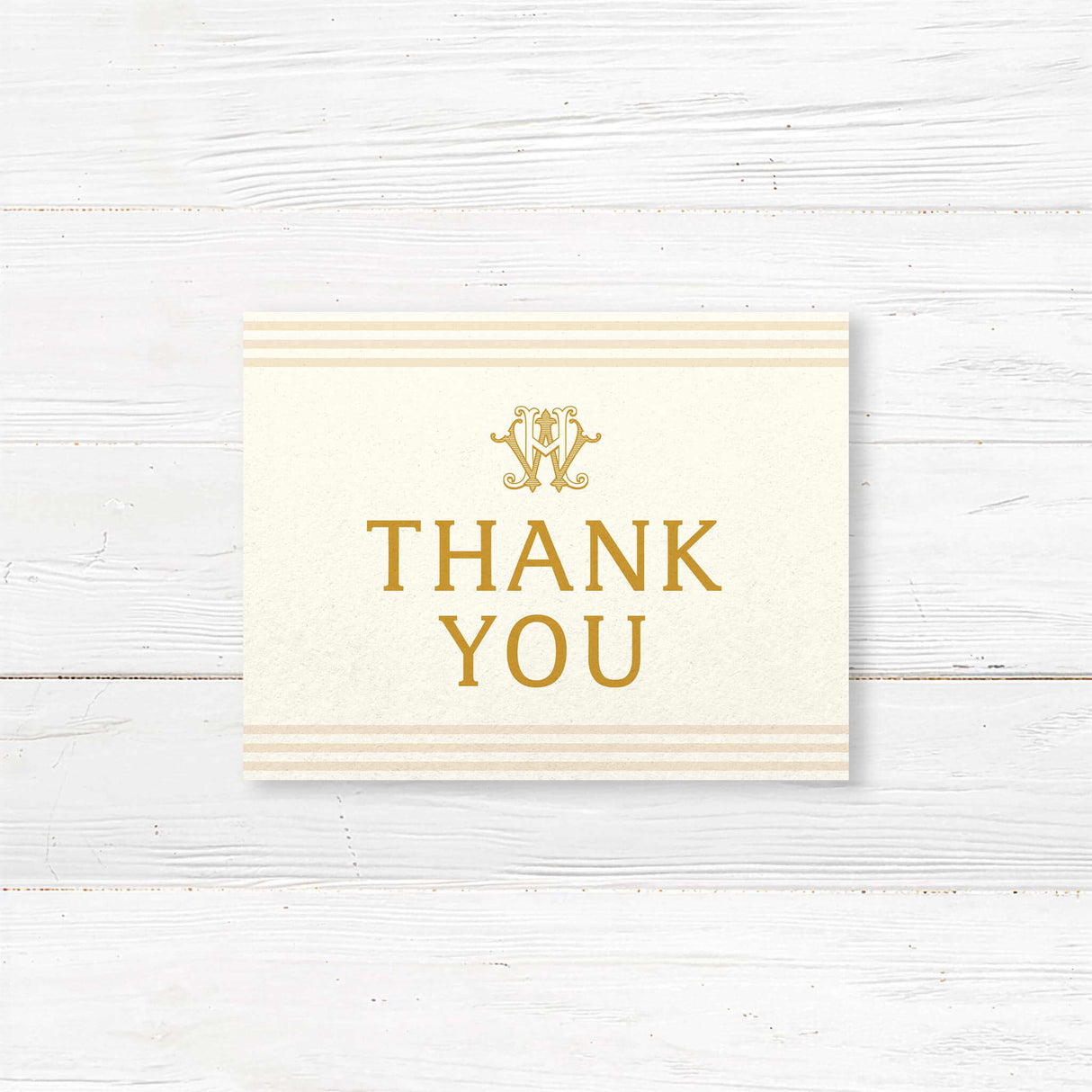 Wedding thank you card with elegant gold serif fonts, cream background, and neutral stripe accents, part of a monogrammed gold wedding stationery suite.