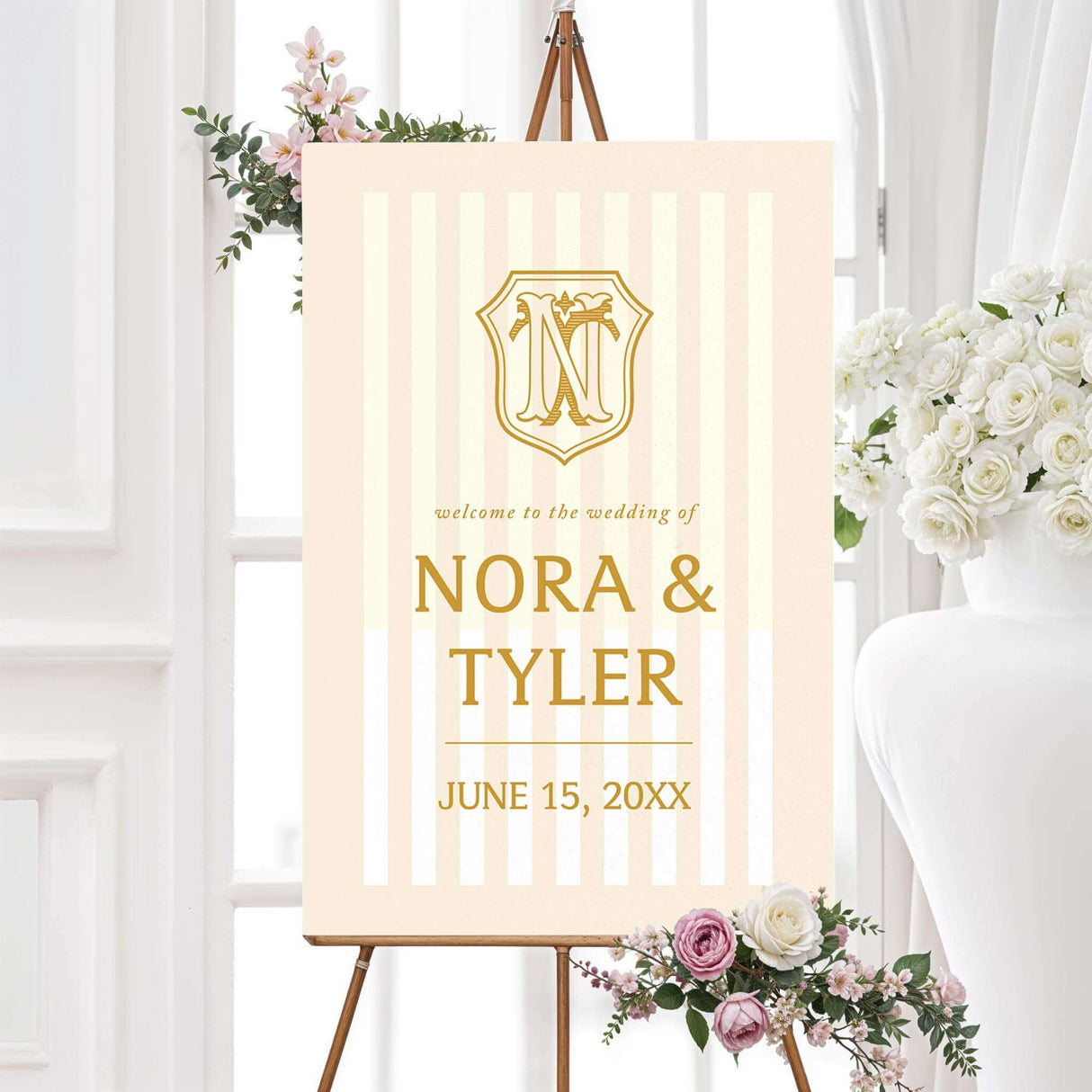 Cream and gold wedding welcome sign with vertical stripes and monogram crest