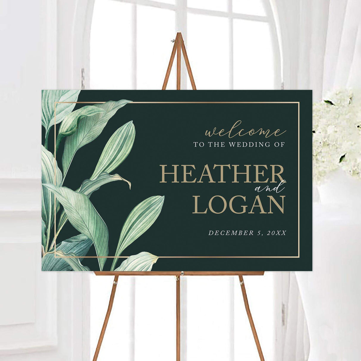 Sweeping greenery wedding welcome sign with sweeping watercolor leaves and a thin gold border. Elegant serif and script lettering displays the couple’s names and personalized wedding date.