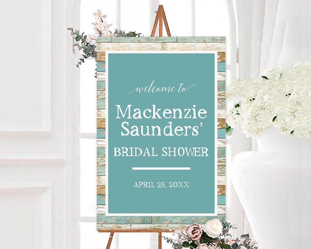 A teal wood bridal shower sign with white text and a rustic wood background. The design features a clean layout with a modern script font.