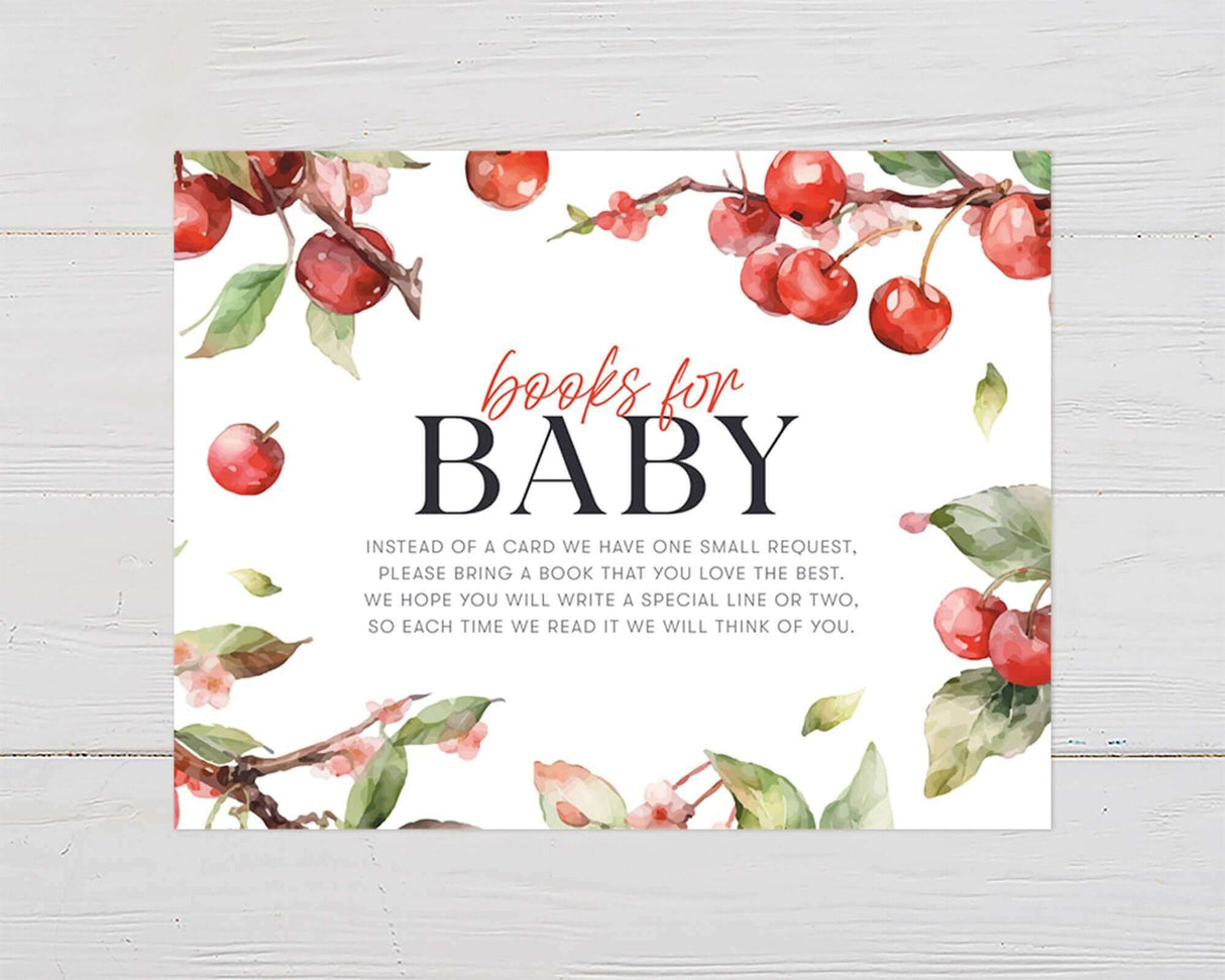 Apple-themed baby shower invitation with watercolor cherries and blossoms on wooden background.