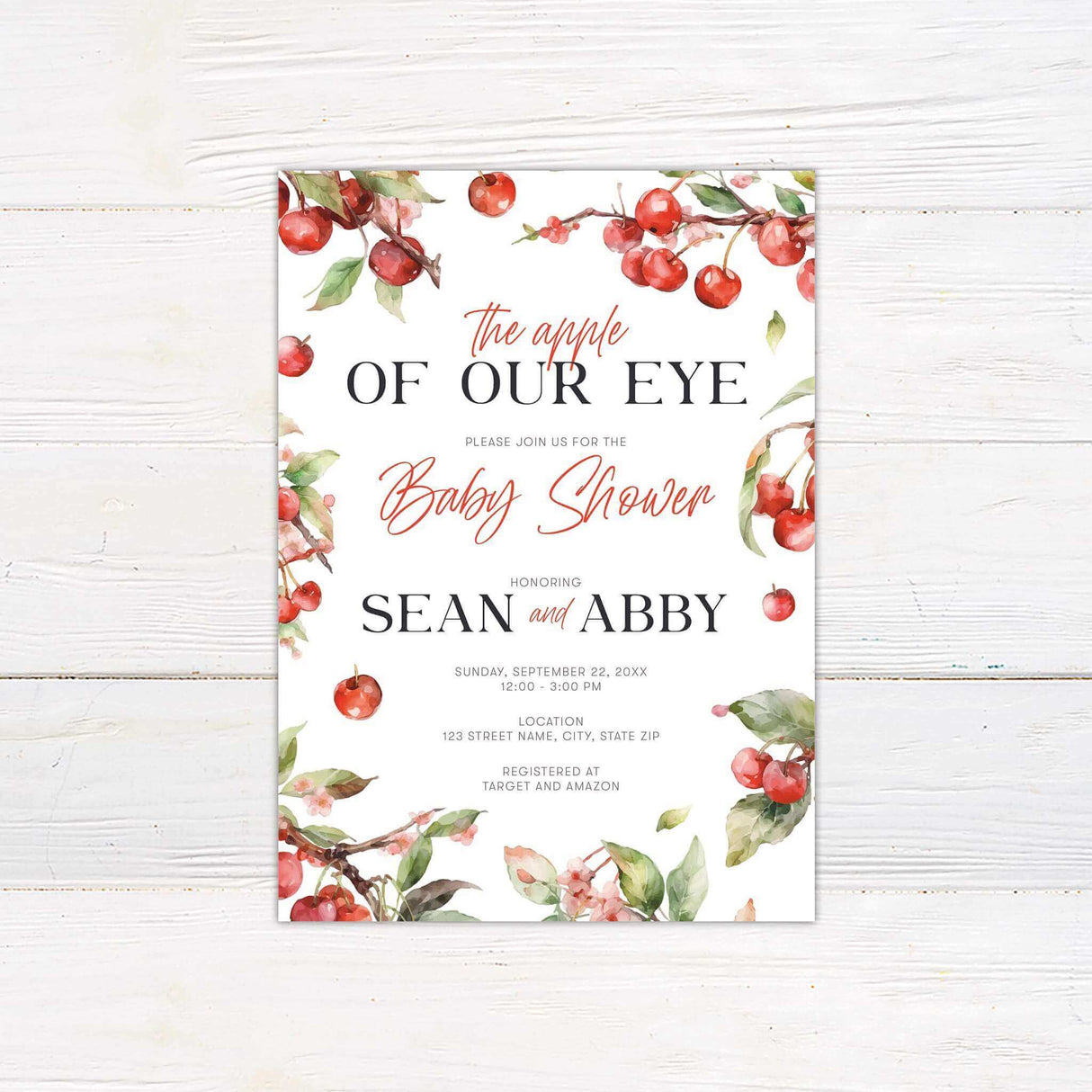 Shower invitation featuring a charming apple and cherry blossom theme. The design includes elegant script and serif fonts with the phrase "The apple of our eye" at the top. Surrounding the text are watercolor-style illustrations of red apples, cherries, and green leaves. The invitation includes event details such as the honorees' names, date, time, location, and registry information. The nature-inspired aesthetic creates a warm and inviting feel, perfect for celebrating a new arrival.