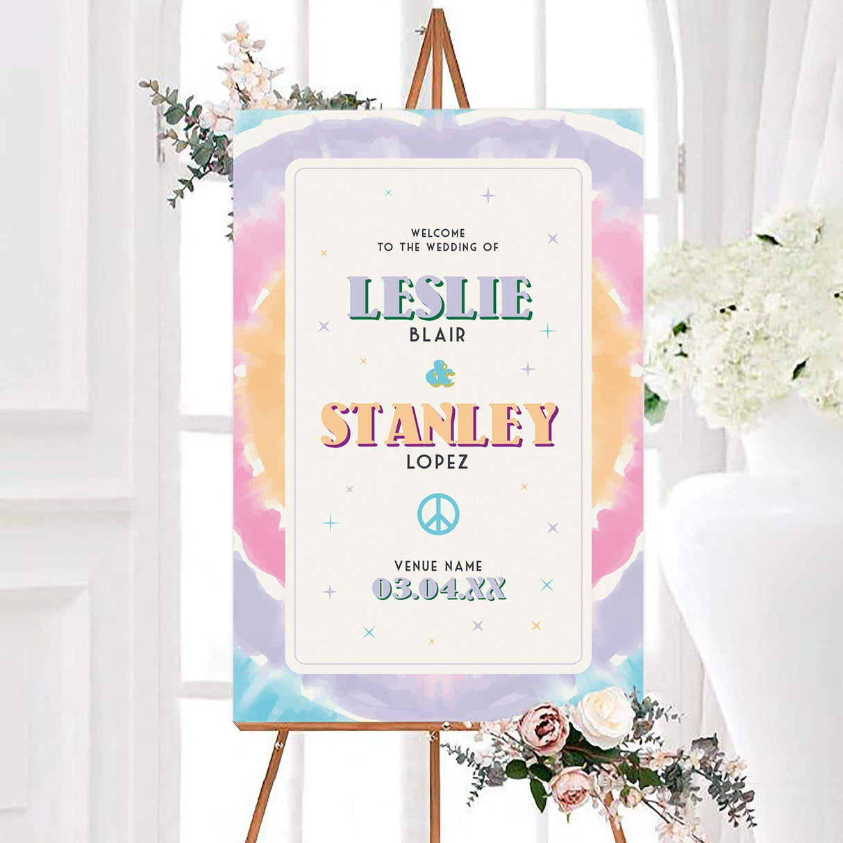Pastel tie dye wedding welcome sign featuring colorful retro typography, starbursts, and a blue peace symbol. The personalized design includes the couple’s names, surnames, venue, and wedding date.