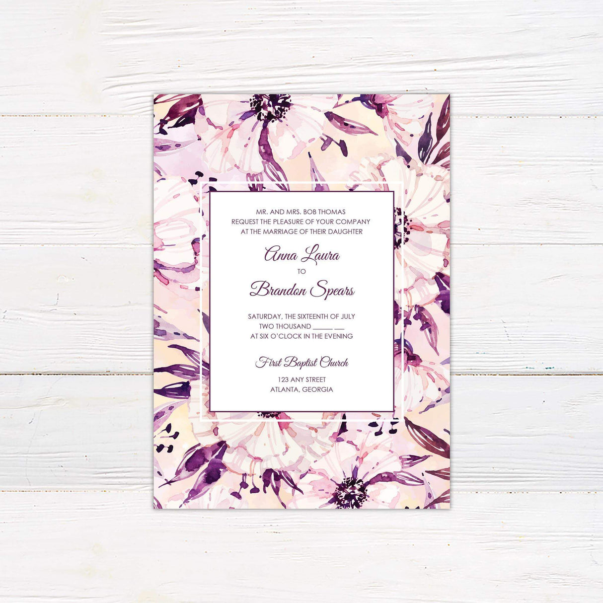 Watercolor floral wedding invitation with bold purple and blush blooms, white center panel, and elegant serif and script fonts.