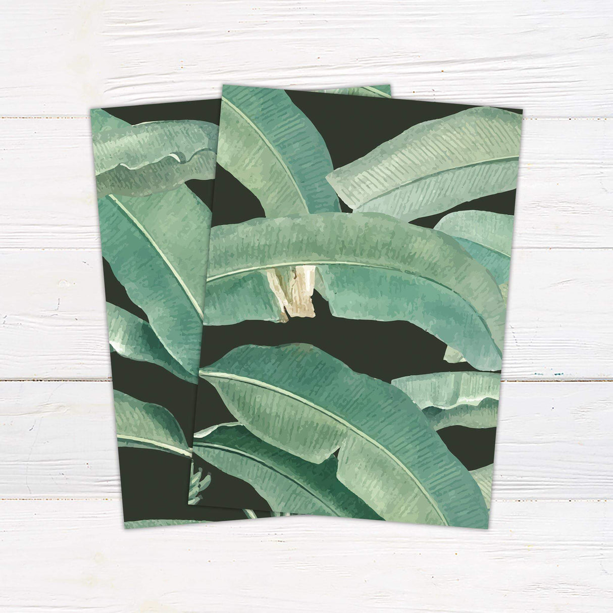 Wedding invitation featuring tropical green leaves on a dark background with a clean white panel and modern serif and script fonts.- back side