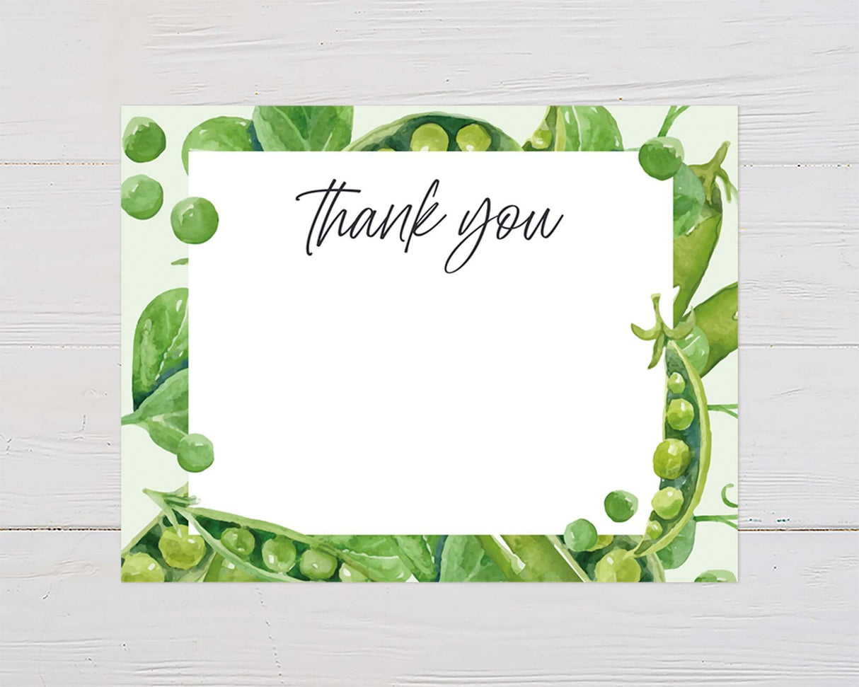 Thank you card with watercolor peas and greenery border on white wood background.