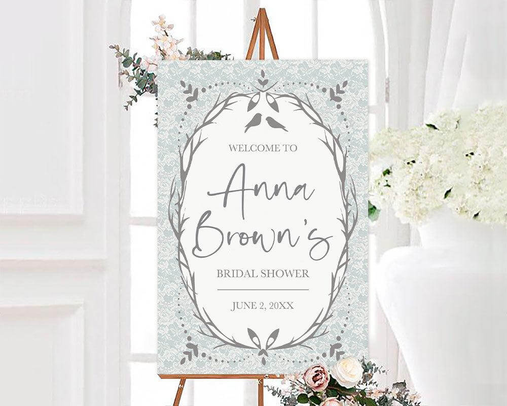 A vintage birds shower sign with birds and a decorative wreath frame. The design features a lace-style background and soft neutral colors.