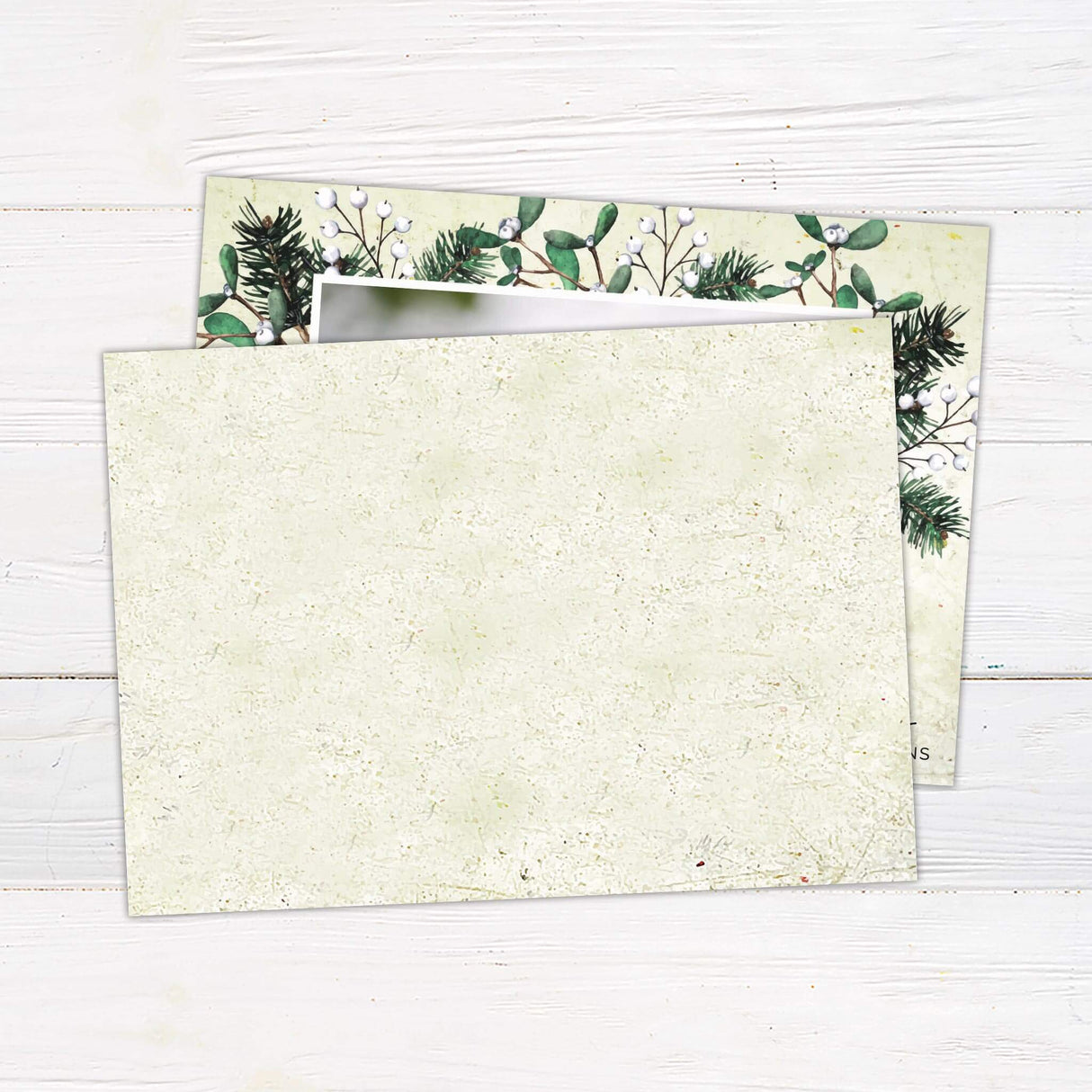 A Christmas card featuring a family photo with pine and mistletoe accents. The design includes a customizable holiday greeting at the bottom. - back.