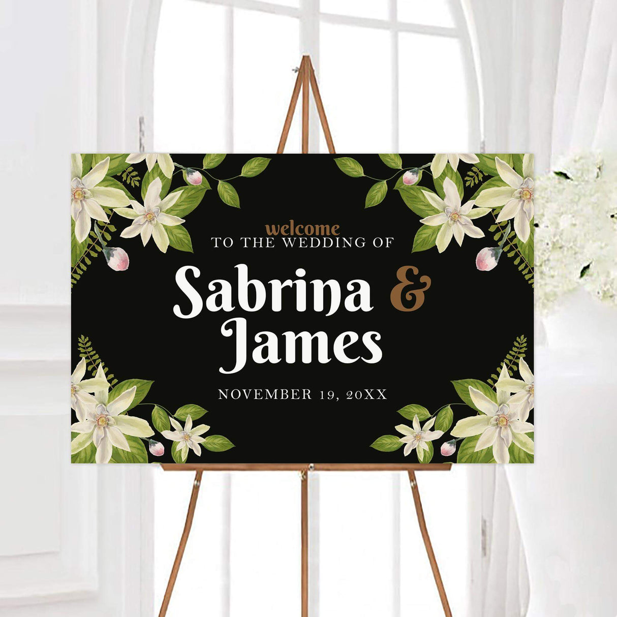 Welcome sign with matching white florals and bold serif text on a dramatic dark background.