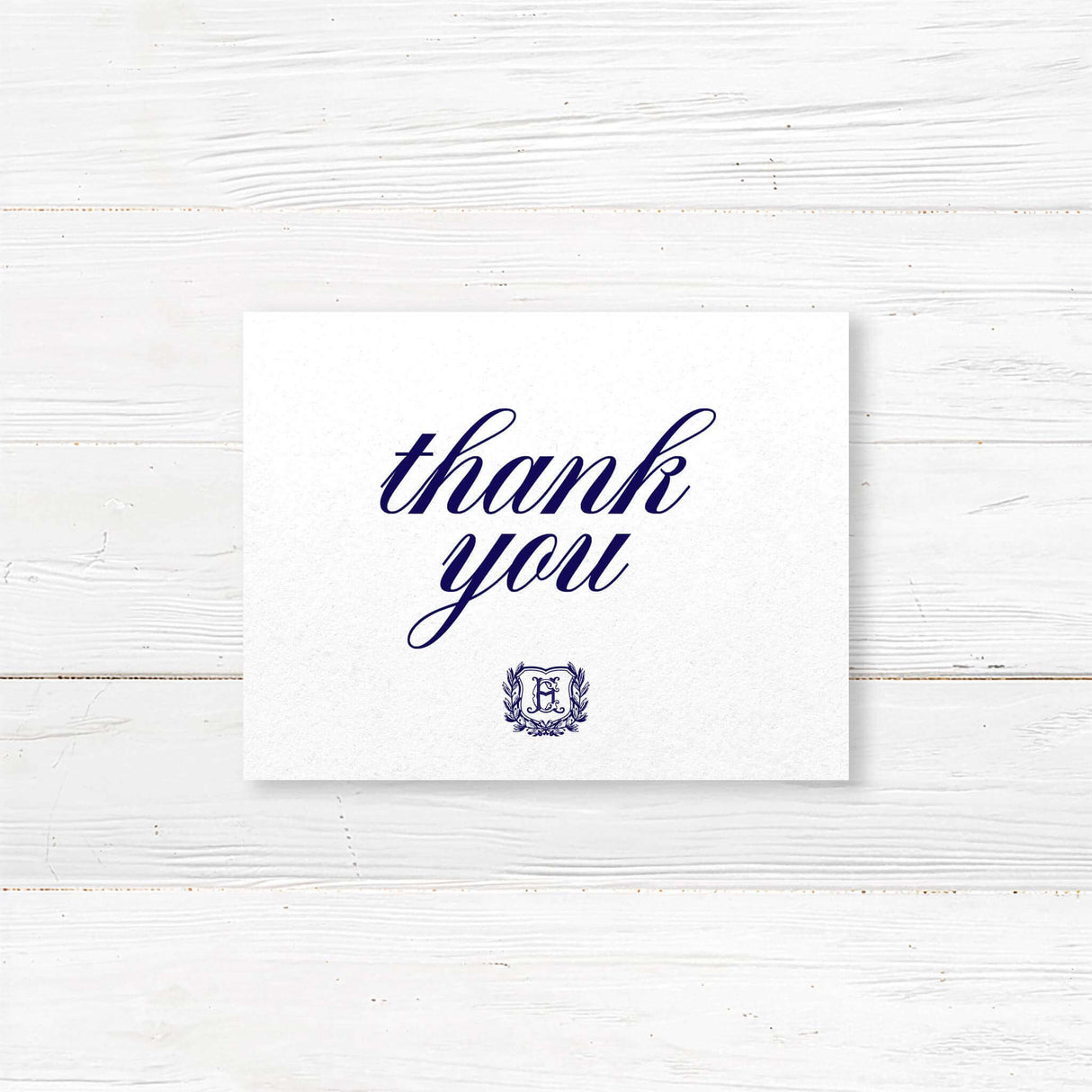 Thank you card with navy monogram crest and formal calligraphy, printed on white textured paper for traditional wedding stationery