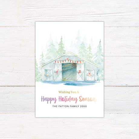 Watercolor holiday card featuring a snowy barn with festive string lights, evergreen trees in the background, and "Wishing You a Happy Holiday Season" in gradient text.