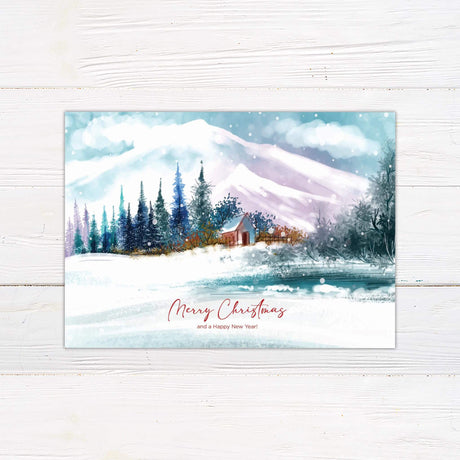 Watercolor winter holiday card with snowy mountain scene, pine trees, and red cabin reading "Merry Christmas and a Happy New Year" in elegant script.