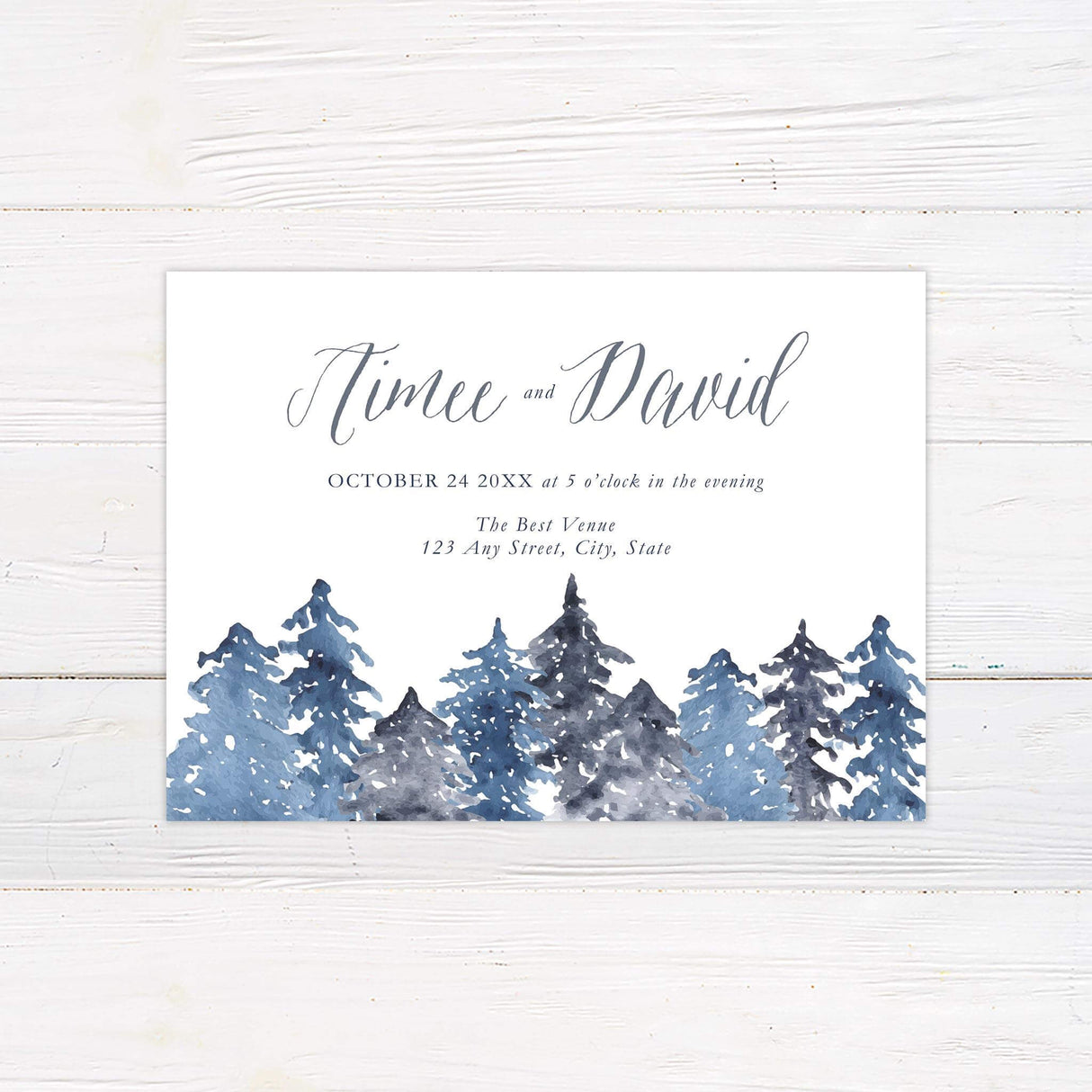 Save the Date card with snowy watercolor pine trees in blue and gray tones and elegant calligraphy.