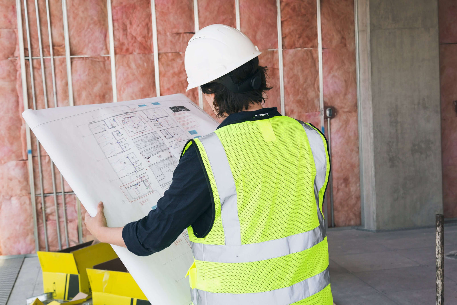 Worker reviewing blueprints in a construction site, showcasing Blueprint Printing Services.