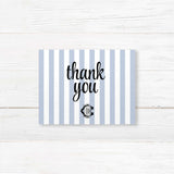 Wedding thank you card with light blue and white vertical stripes and elegant monogram crest, coordinated with matching wedding suite for a refined finish.