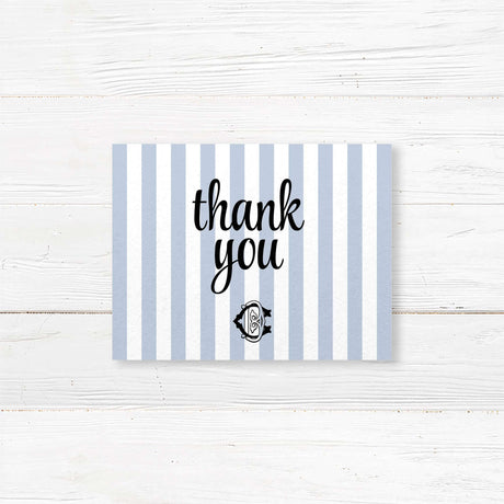 Wedding thank you card with light blue and white vertical stripes and elegant monogram crest, coordinated with matching wedding suite for a refined finish.