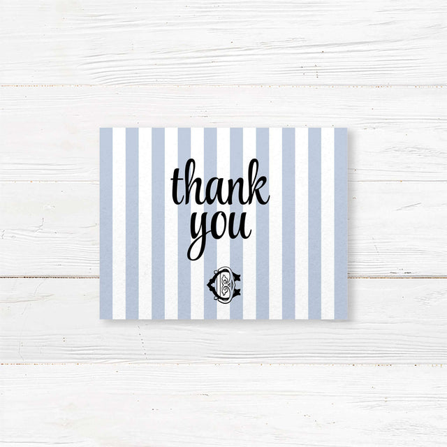 Wedding thank you card with light blue and white vertical stripes and elegant monogram crest, coordinated with matching wedding suite for a refined finish.