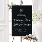 Wedding welcome sign with black background, white ornate monogram crest, and elegant serif and calligraphy fonts, matching the Black Entwined Initials wedding suite.