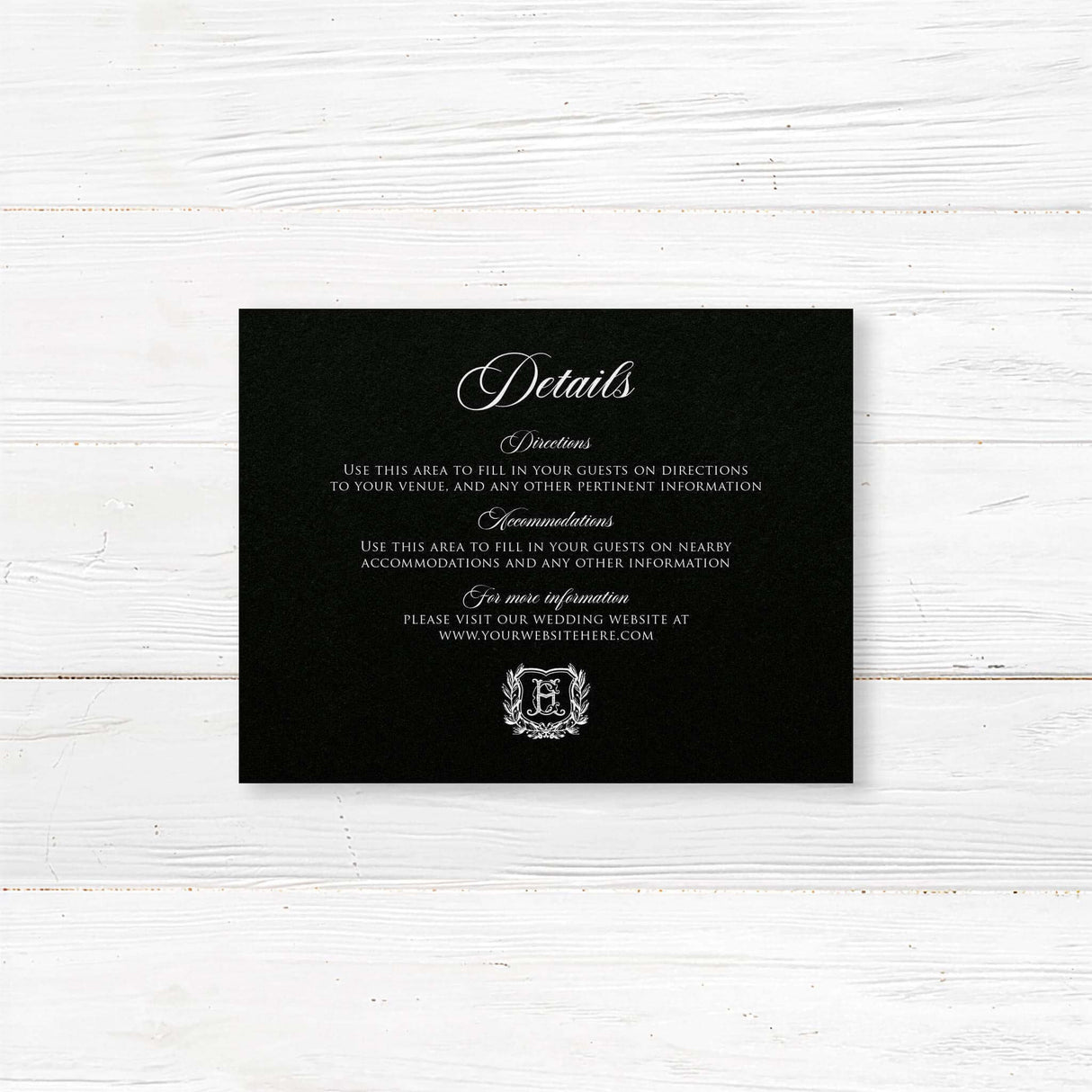 Wedding detail card with a black background, white serif and script fonts, and vintage shield monogram wreath accent. Ideal for formal or vintage wedding stationery suites.