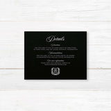 Wedding detail card with a black background, white serif and script fonts, and vintage shield monogram wreath accent. Ideal for formal or vintage wedding stationery suites.